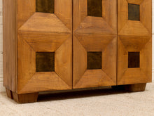 Load image into Gallery viewer, A close-up of a mid-century modern wooden cabinet with geometric panel doors in a warm medium brown finish, featuring dark inset square panels and standing on a light beige carpet.
