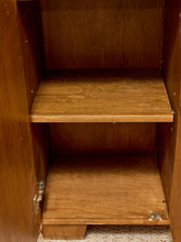Load image into Gallery viewer, An empty wooden storage cabinet with two shelves, showing the interior wood grain and metal hinges on a neutral textured floor.
