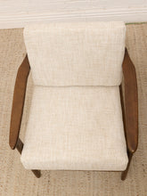 Load image into Gallery viewer, A mid-century modern armchair with a textured cream linen upholstery and a dark brown wooden frame, shown from a top-down perspective on a woven rug.
