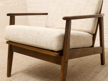 Load image into Gallery viewer, A mid-century modern accent chair with a dark brown wooden frame and textured cream bouclé upholstery, set against a white brick wall and beige rug.
