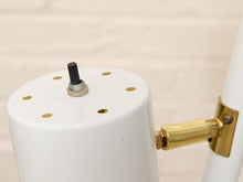 Load image into Gallery viewer, Close-up of a white cylindrical lamp shade or fixture body with a brass arm joint and a small black switch on top, against a light neutral background.
