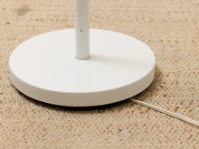 Load image into Gallery viewer, Close-up of a white circular lamp base on a beige textured carpet with part of the power cord visible.
