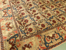 Load image into Gallery viewer, A close-up view of an ornate traditional area rug with a beige background, featuring intricate floral motifs in red, blue, and brown, and a detailed border.
