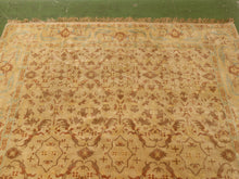 Load image into Gallery viewer, A traditional oriental-style area rug with an intricate floral and geometric pattern in beige, rust brown, and light blue, laid out on a green floor.
