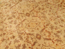 Load image into Gallery viewer, A close-up of a traditional patterned rug with a warm beige background and brown, rust, and muted orange floral and geometric motifs.

