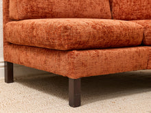 Load image into Gallery viewer, Close-up of an orange textured fabric sofa cushion and base with dark wooden legs on a light carpet.
