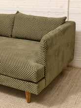 Load image into Gallery viewer, A close-up of a mid-century modern loveseat featuring olive green and beige checkered upholstery, wooden legs, and a textured neutral rug against a white brick wall.
