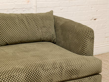 Load image into Gallery viewer, A close-up of an olive green textured fabric sofa with a matching back cushion, set against a white brick wall background.
