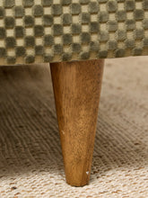 Load image into Gallery viewer, Close-up of a mid-century modern upholstered chair or stool leg, featuring a tapered medium-brown wooden leg and a textured checkered fabric upholstery in beige and olive green.
