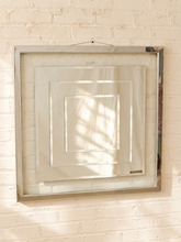 Load image into Gallery viewer, A square mirrored wall mirror with a polished silver frame, mounted on a white painted brick wall.

