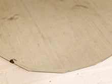 Load image into Gallery viewer, A close-up of a large, circular mirror with a warm, champagne-beige tinted glass surface, resting on a textured white surface.
