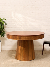Load image into Gallery viewer, Round burl-style wood dining table with glossy figured top, reeded apron and cylindrical pedestal base

