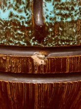 Load image into Gallery viewer, Close-up of a ceramic vessel showing a textured brown glaze with turquoise accents and a vertical handle detail.
