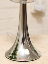 Load image into Gallery viewer, A close-up of a polished silver metal pedestal lamp base with a flared circular shade, shown on a light beige surface against a softly blurred indoor background.
