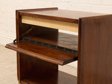 Load image into Gallery viewer, A close-up of a mid-century modern wooden desk with a dark brown finish, featuring a pull-out keyboard tray and a light wood top surface, set against a white brick wall background.
