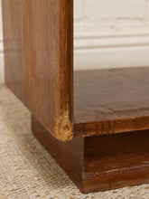 Load image into Gallery viewer, Close-up of a dark brown wooden furniture piece, showing the corner joint and worn wood finish on the shelf edge, resting on a woven beige rug.
