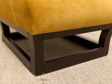 Load image into Gallery viewer, Close-up of an upholstered ottoman or bench with mustard yellow fabric cushioning and a dark brown wooden frame, shown on a textured beige carpet.
