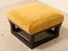 Load image into Gallery viewer, A square ottoman with a mustard yellow velvet cushion and a dark brown wooden frame, shown on a textured beige rug.
