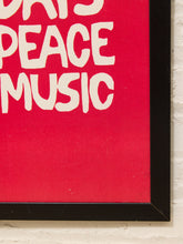 Load image into Gallery viewer, A close-up of a framed wall art print with a bright red background and large white hand-drawn text reading 'PEACE MUSIC', mounted on a white brick wall.
