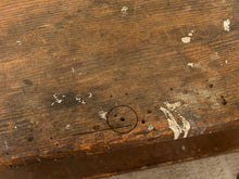 Load image into Gallery viewer, A close-up of a weathered, rustic wooden surface with visible grain, scratches, peeling white paint, and a small hand-drawn circle and line marking near the center.

