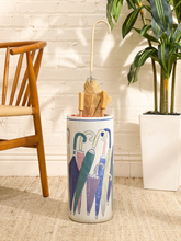 Load image into Gallery viewer, Vintage white ceramic umbrella stand decorated with colorful blue, green, pink, and gray umbrella illustrations

