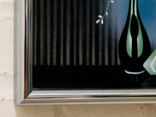 Load image into Gallery viewer, Close-up of a framed wall art print showing a stylized black vase with green and white accents against a dark background, mounted on a light beige wall.
