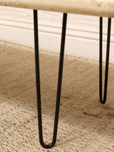 Load image into Gallery viewer, Close-up of a table leg with a black U-shaped metal hairpin base, set on a textured beige woven rug against a white wall.
