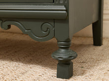 Load image into Gallery viewer, Close-up of a dark gray painted wooden furniture piece, showing a decorative carved apron and turned leg on a beige woven rug.
