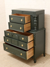 Load image into Gallery viewer, A dark green painted wooden chest of drawers with five open drawers showing light wood interiors and brass knobs, set against a white brick wall and beige carpet.
