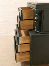 Load image into Gallery viewer, A dark painted wooden dresser with several drawers pulled open, showing the natural wood interiors. The dresser has ornate turned legs and is photographed indoors against a white brick wall and light carpet.
