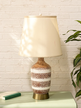 Load image into Gallery viewer, Vintage textured ceramic table lamp with brown and white horizontal stripes, brass-tone base, and tall cream fabric shade
