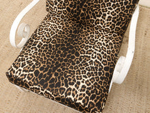 Load image into Gallery viewer, Leopard print outdoor chair cushion on a white metal patio chair over a woven jute rug.
