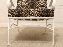 Load image into Gallery viewer, A white metal outdoor armchair with leopard-print cushions on the seat and back, set against a light brick wall and textured beige rug.
