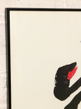 Load image into Gallery viewer, A framed abstract art print featuring bold black brushstrokes with a vibrant red accent on a warm cream background, set in a black frame against a white brick wall.

