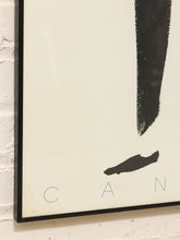 Load image into Gallery viewer, A close-up of a framed abstract art print hanging on a white brick wall. The print features a large black vertical brushstroke, a smaller black horizontal brushstroke near the bottom, and the letters 'C', 'A', 'N' spaced out along the bottom edge on an off-white background.
