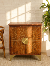 Load image into Gallery viewer, Vintage wood cabinet with radiating sunburst front, circular brass-tone center hardware, and tapered feet
