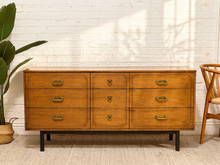 Load image into Gallery viewer, Vintage mid-century wood dresser with Formica top, multiple drawers, brass-tone drop pulls, and slim dark legs
