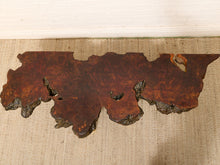 Load image into Gallery viewer, A rustic live-edge wooden wall art piece with rich reddish-brown and dark brown wood grain, displayed on a beige woven rug against a white wall.
