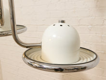 Load image into Gallery viewer, A close-up of a vintage-style white ceramic salt or pepper shaker with a chrome metal base and wall mount, set against a white brick wall.
