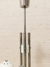 Load image into Gallery viewer, A close-up of a mid-century modern floor lamp with a polished chrome metal frame and a white ceramic shade, set against a white brick wall background.
