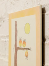 Load image into Gallery viewer, A vertical art print featuring a whimsical illustration of three orange owls perched on a tree branch under a yellow sun, displayed against a white brick wall.
