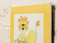 Load image into Gallery viewer, A square art print featuring a whimsical cartoon lion with a fiery orange-yellow mane and a long tail ending in a flower, mounted against a white brick wall.

