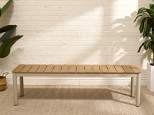 Load image into Gallery viewer, Modern outdoor bench with warm faux teak composite slatted seat and rounded light-colored legs
