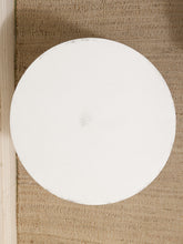 Load image into Gallery viewer, A round white plate or shallow dish photographed from above on a woven beige fabric surface next to a light wood edge.
