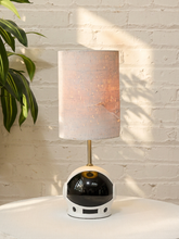 Load image into Gallery viewer, Vintage astronaut helmet table lamp with glossy black visor and tall cylindrical fabric shade
