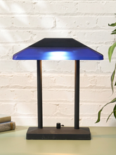 Load image into Gallery viewer, Vintage postmodern desk lamp with cobalt blue angular shade, black stepped top, twin supports, and rectangular base
