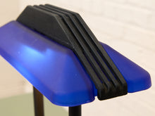 Load image into Gallery viewer, Close-up of a blue translucent plastic component with a black ribbed mounting piece attached, photographed against a light neutral background.
