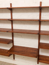 Load image into Gallery viewer, Mid-century modern wall-mounted wooden shelving with a warm medium-brown finish, mounted on a white painted brick wall.
