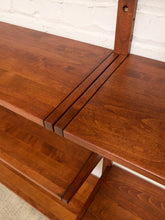 Load image into Gallery viewer, Close-up of a mid-century modern wooden bookshelf with a warm reddish-brown finish, featuring a slatted center divider and a white brick wall background.
