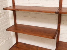 Load image into Gallery viewer, A close-up of a wooden wall-mounted shelving unit with three visible shelves, shown against a white painted brick wall.

